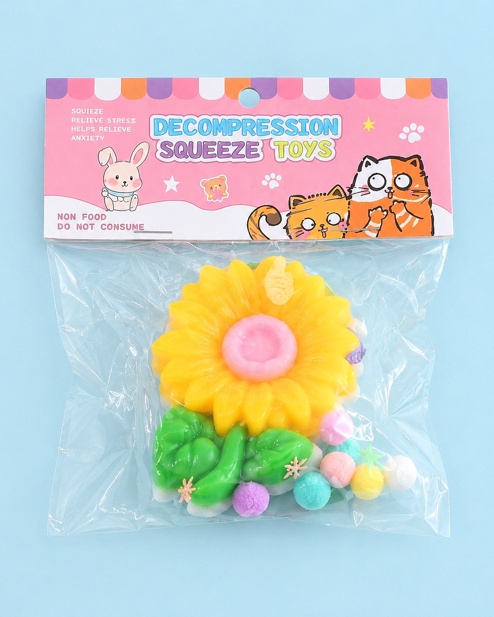 a yellow flower-shaped decompression squishy toy with glossy petals, green leaves, mini decorative accents, and pastel pom poms
