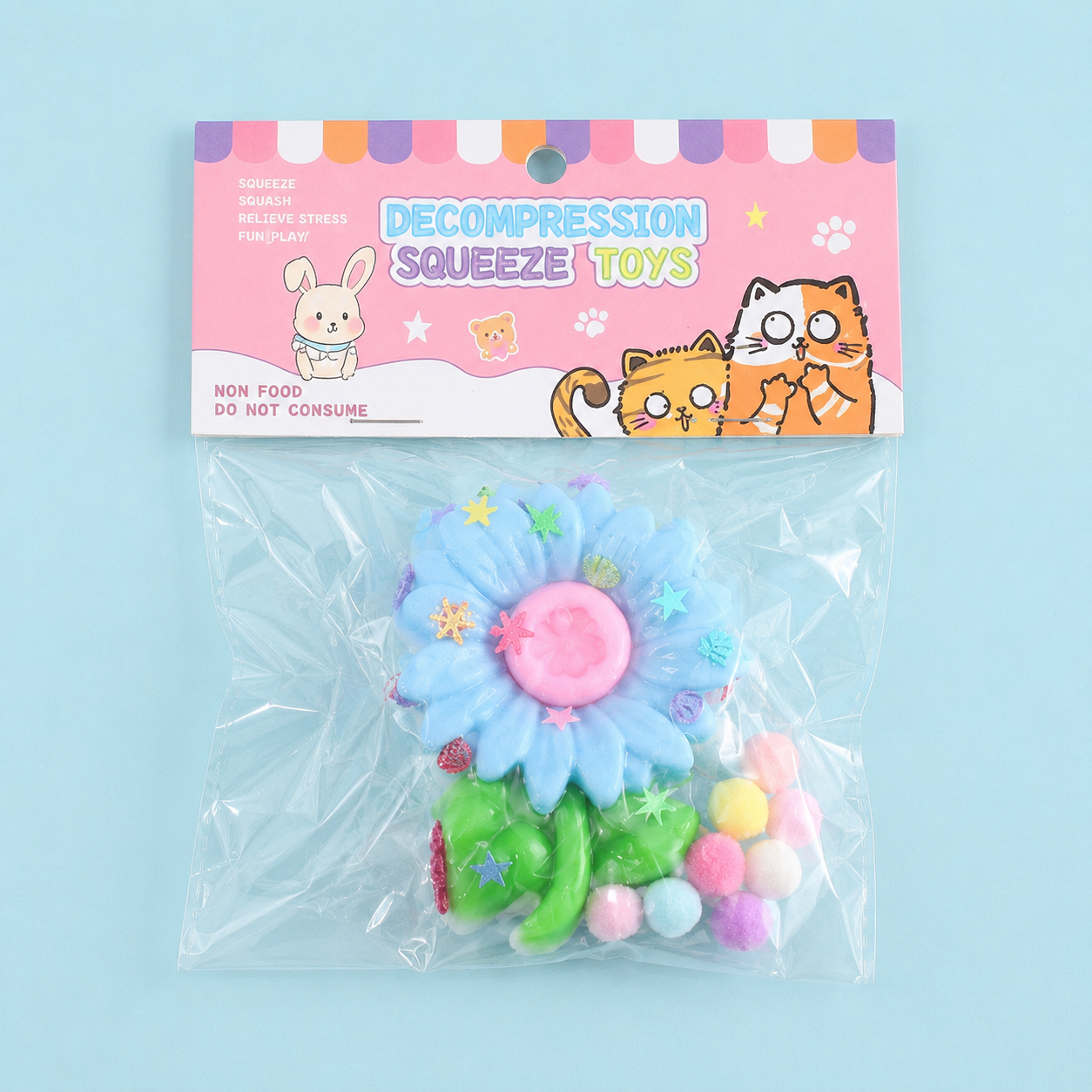 a blue flower-shaped decompression squishy toy with glossy petals, green leaves, mini decorative accents, and pastel pom poms