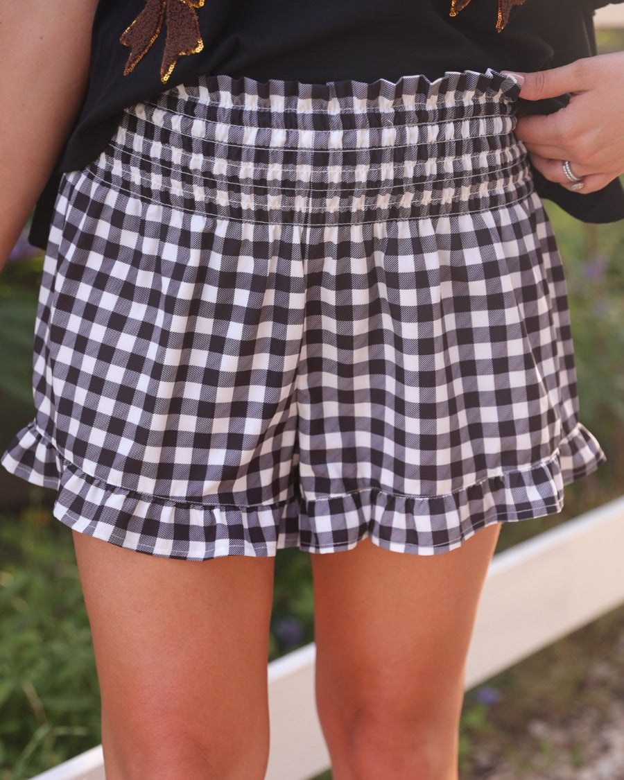 high-waisted gingham shorts with smocked waistband and ruffle hem in black