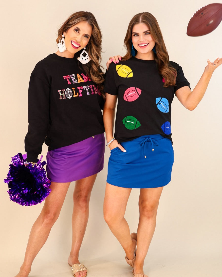 black long-sleeve sweatshirt made from soft mid-weight fabric with a crew neckline, straight hem, and bold multicolored varsity-style chenille patches that spell out 'TEAM HALFTIME' across the front chest
