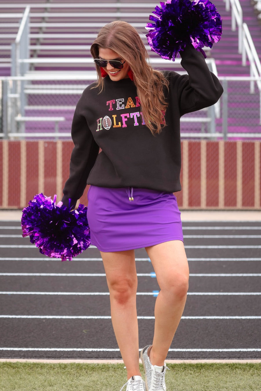 black long-sleeve sweatshirt made from soft mid-weight fabric with a crew neckline, straight hem, and bold multicolored varsity-style chenille patches that spell out 'TEAM HALFTIME' across the front chest
