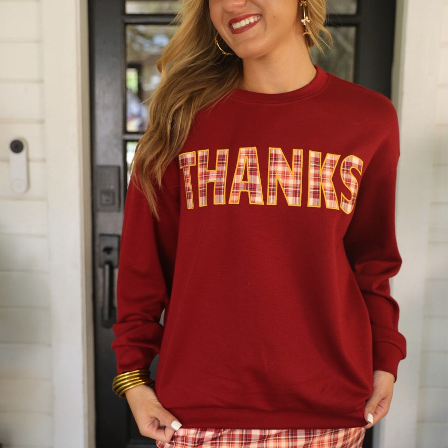 long-sleeve burgundy pullover with plaid 'THANKS' letters outlined in embroidery on a soft fabric