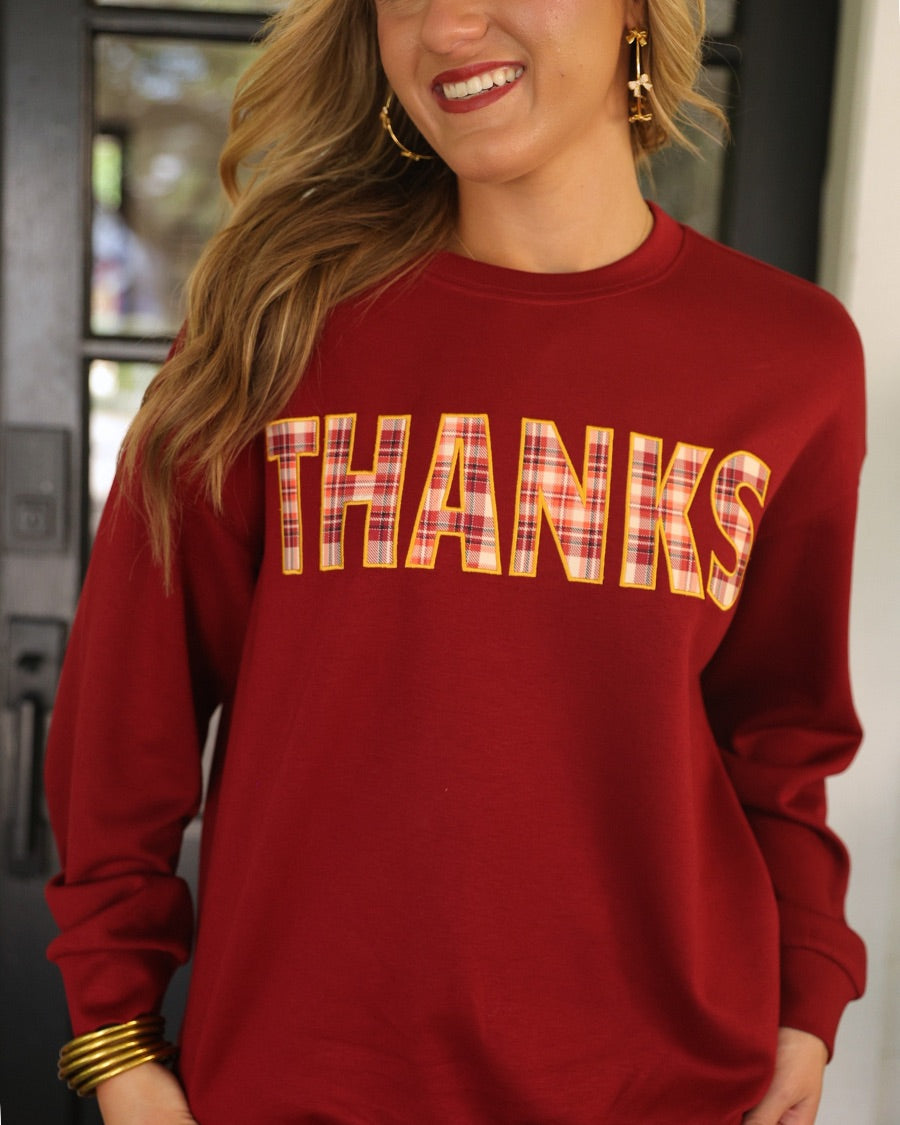 long-sleeve burgundy pullover with plaid 'THANKS' letters outlined in embroidery on a soft fabric