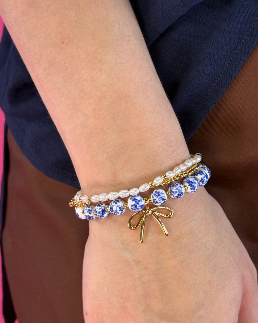three-piece bracelet set with a charming mix of brass, sheer pearls, floral-patterned beads, and a dainty bow accent
