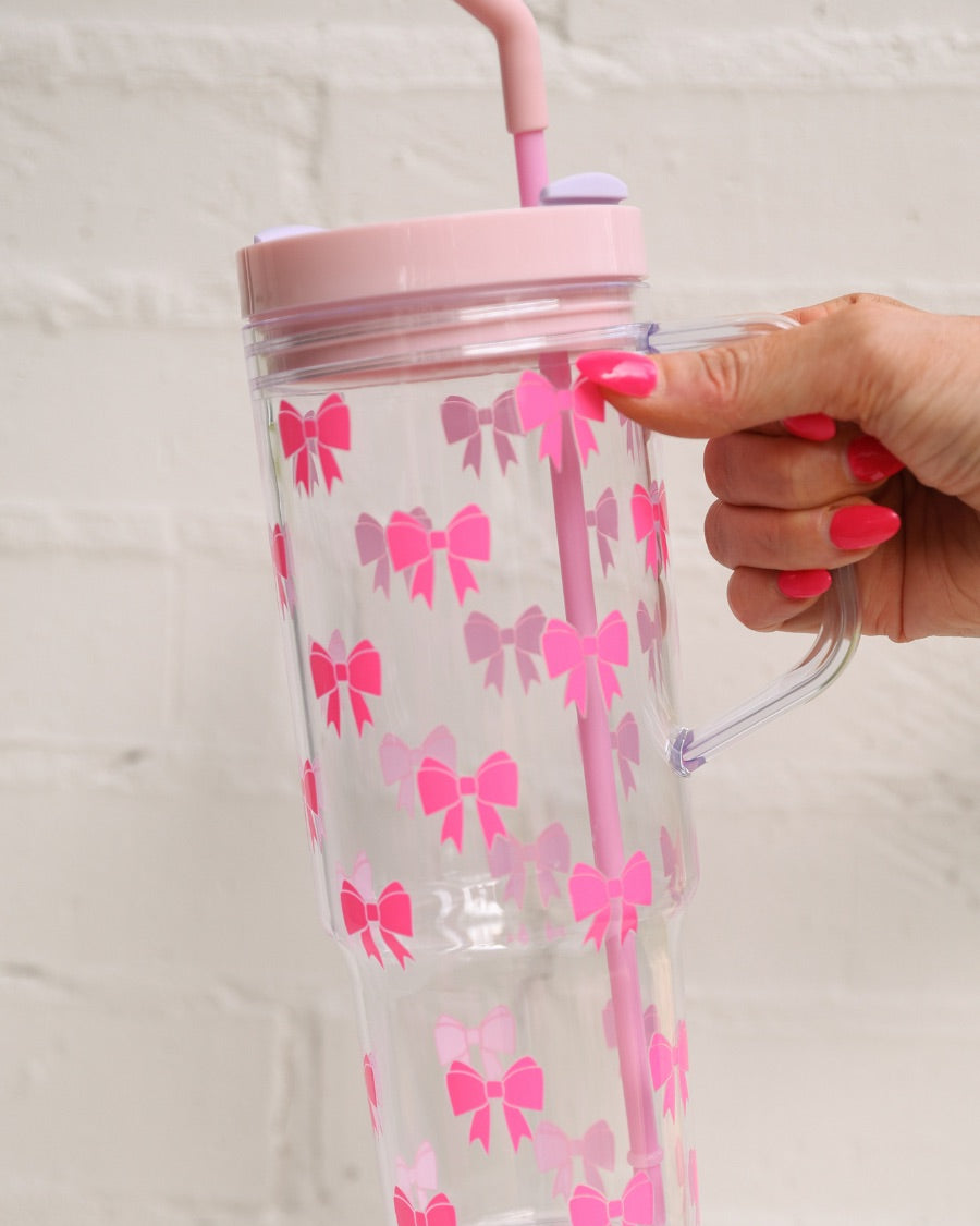 40-ounce pink bow acrylic tumbler with a reusable straw (pink), flexible mouthpiece (pastel pink), handle, screw-on lid (pastel pink with a lavender rotate lid tab), and car cup holder compatible