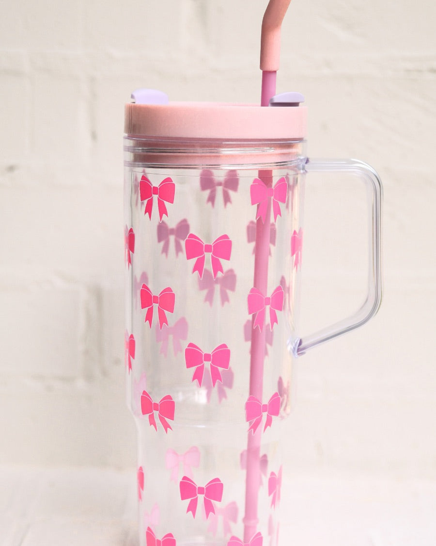40-ounce pink bow acrylic tumbler with a reusable straw (pink), flexible mouthpiece (pastel pink), handle, screw-on lid (pastel pink with a lavender rotate lid tab), and car cup holder compatible
