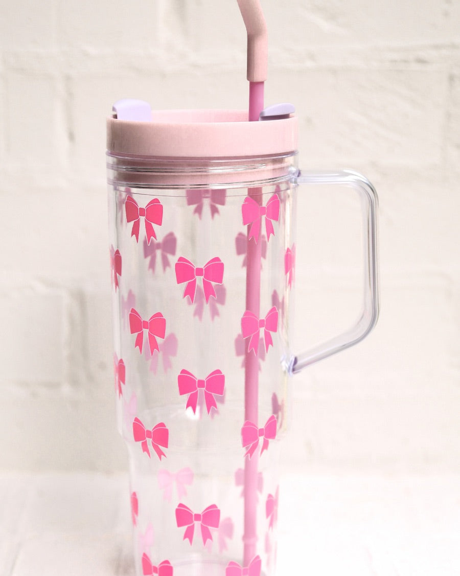 40-ounce pink bow acrylic tumbler with a reusable straw (pink), flexible mouthpiece (pastel pink), handle, screw-on lid (pastel pink with a lavender rotate lid tab), and car cup holder compatible