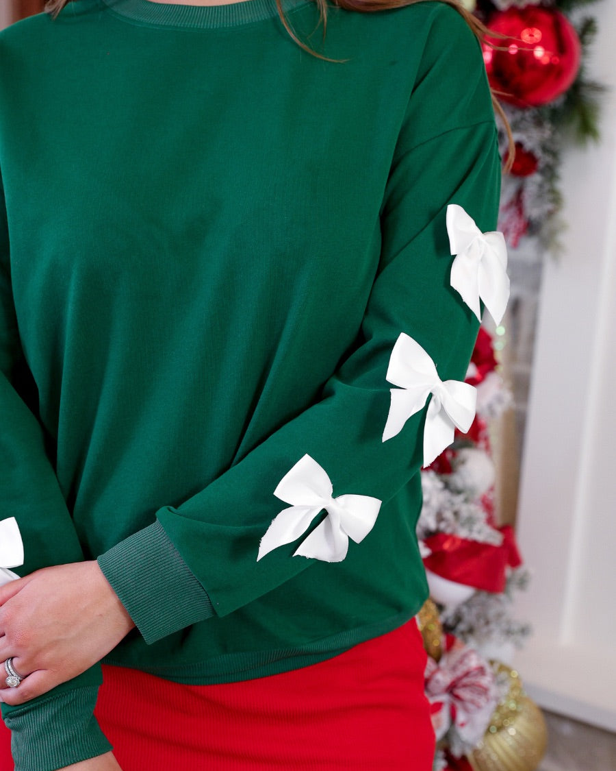a rich green long-sleeve pullover accented with satin bows cascading down each sleeve