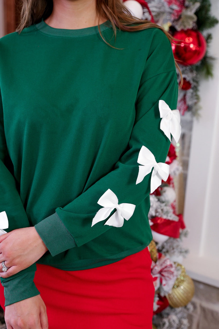 a rich green long-sleeve pullover accented with satin bows cascading down each sleeve