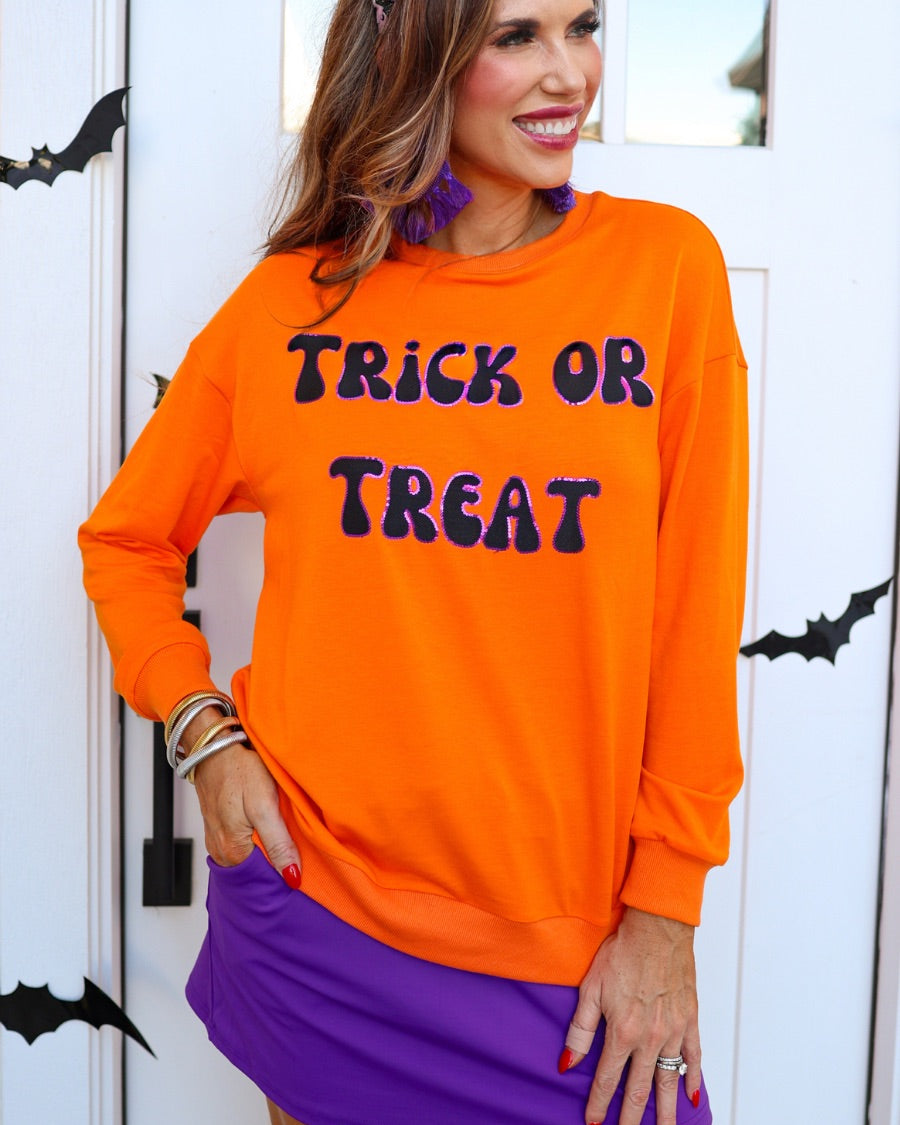 a long-sleeve sweatshirt with plush black embroidered 'TRICK OR TREAT' appliquรฉ lettering, purple sequin outlining, crew neckline, ribbed cuffs, a banded hem, and a relaxed fit for a classic silhouette