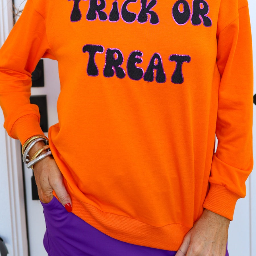 a long-sleeve sweatshirt with plush black embroidered 'TRICK OR TREAT' appliquรฉ lettering, purple sequin outlining, crew neckline, ribbed cuffs, a banded hem, and a relaxed fit for a classic silhouette