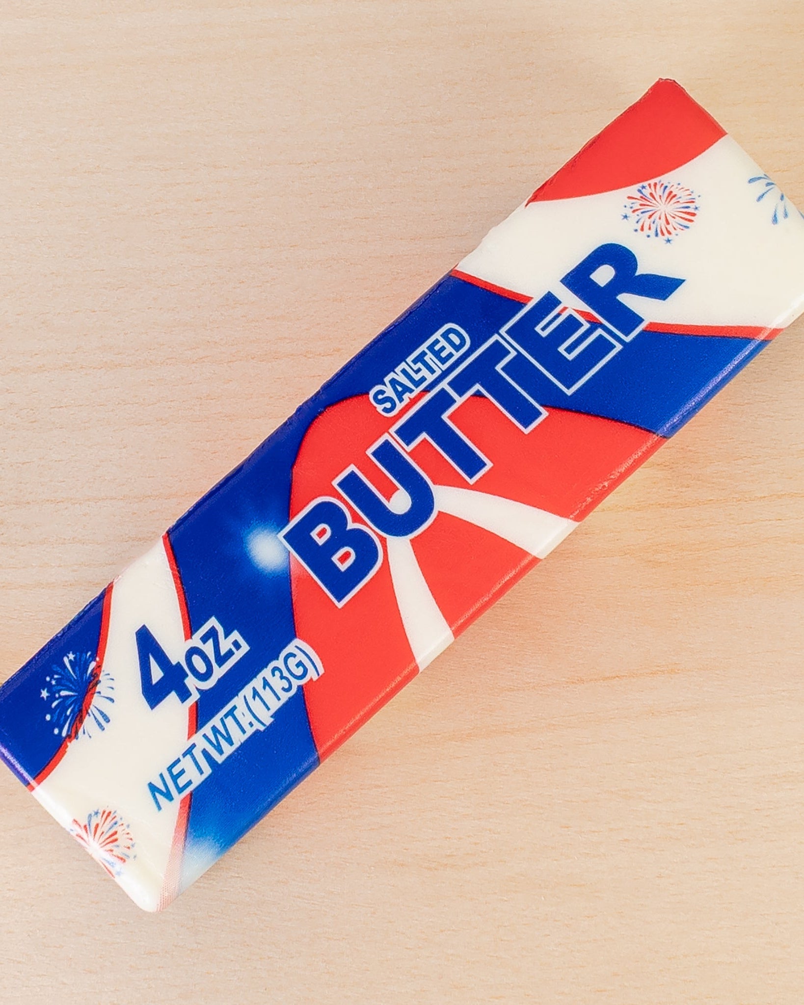 a 4oz USA-inspired butter-stick foam fidget toy made from slow rise polyurethane (PU) foam with a soft texture, a patriotic design (red, white, and blue), playful printed lettering, and individual packaging