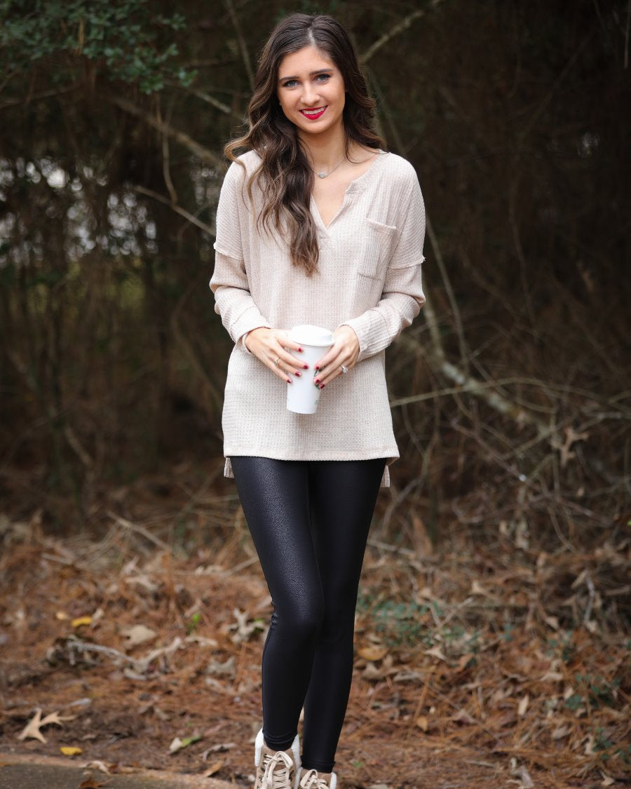 made in the USA long-sleeve top crafted from soft material with waffle knit texturing, a drop shoulder, a v-neck neckline, a front chest pocket, a hi-low side split hem, and a relaxed fit that falls into a straight hemline in oatmeal