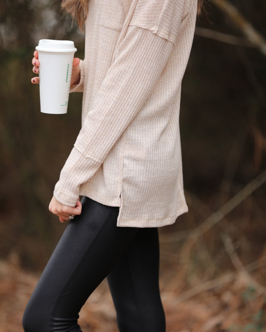 made in the USA long-sleeve top crafted from soft material with waffle knit texturing, a drop shoulder, a v-neck neckline, a front chest pocket, a hi-low side split hem, and a relaxed fit that falls into a straight hemline in oatmeal