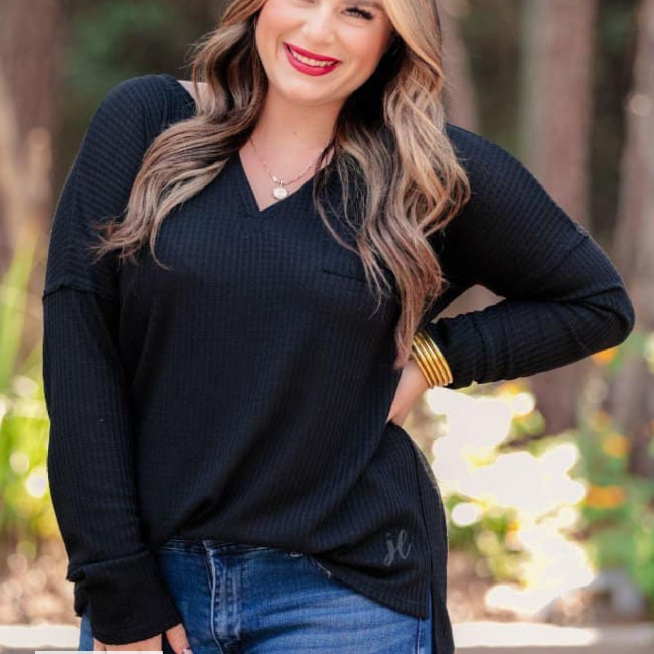 made in the USA long-sleeve top crafted from soft material with waffle knit texturing, a drop shoulder, a v-neck neckline, a front chest pocket, a hi-low side split hem, and a relaxed fit that falls into a straight hemline in black