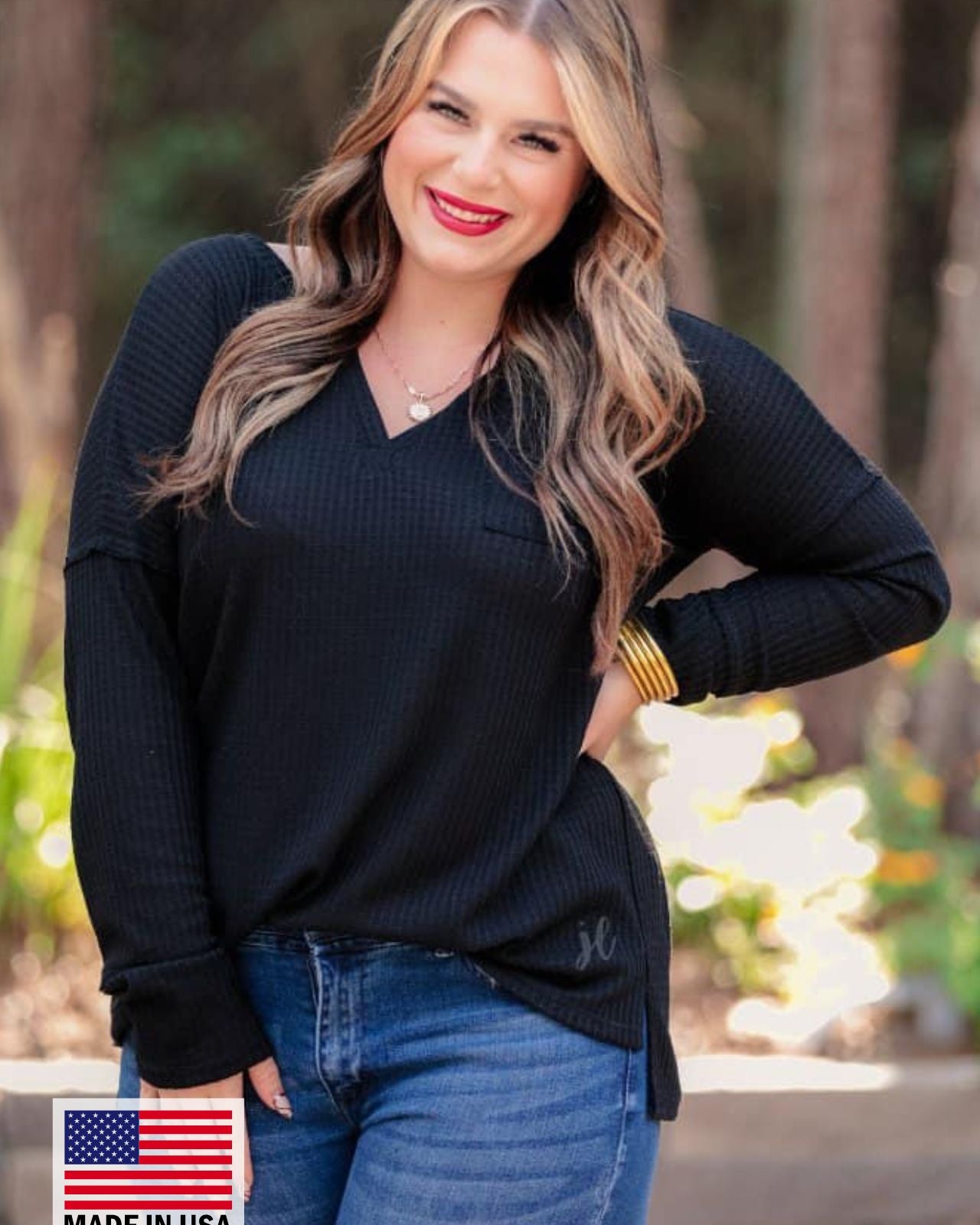made in the USA long-sleeve top crafted from soft material with waffle knit texturing, a drop shoulder, a v-neck neckline, a front chest pocket, a hi-low side split hem, and a relaxed fit that falls into a straight hemline in black