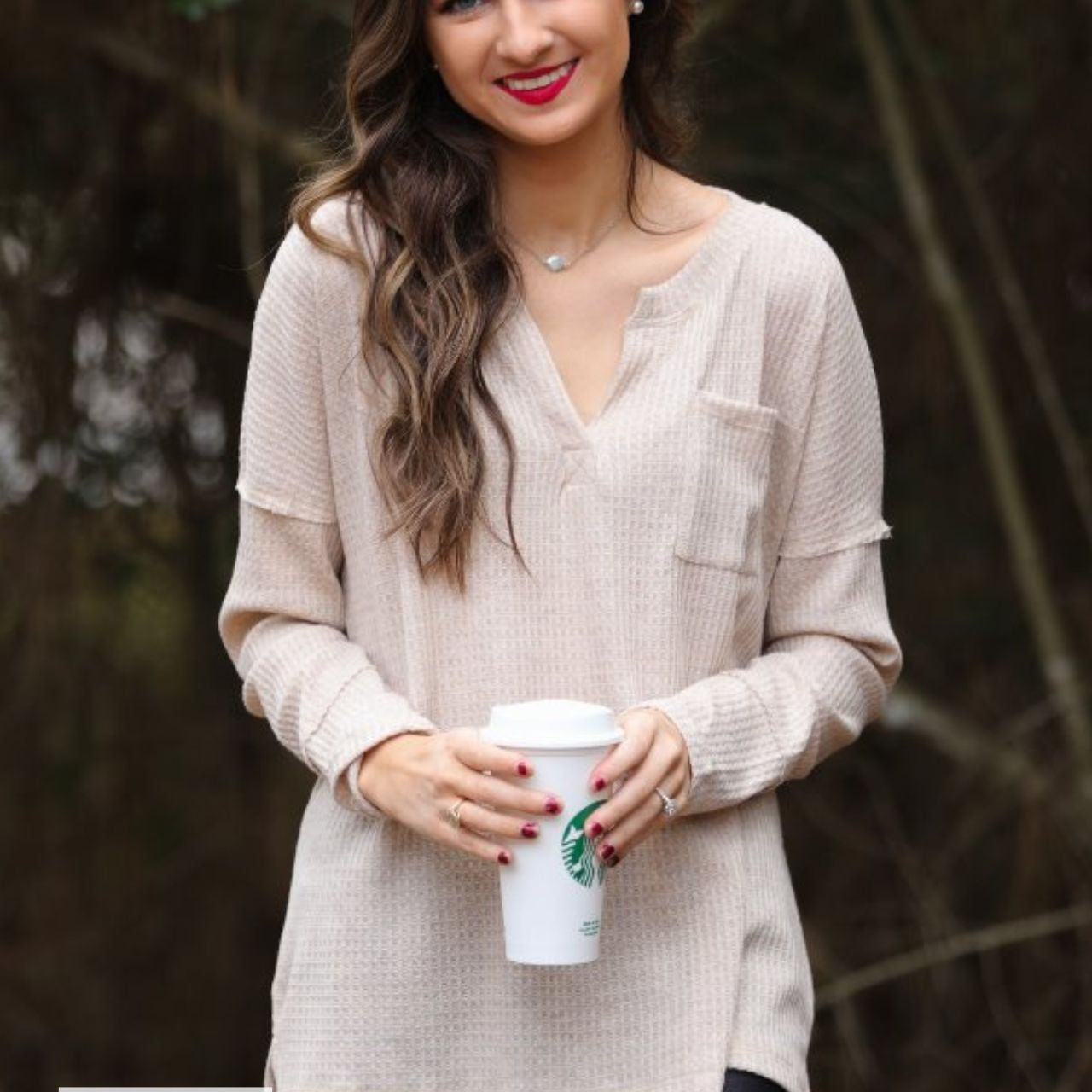 made in the USA long-sleeve top crafted from soft material with waffle knit texturing, a drop shoulder, a v-neck neckline, a front chest pocket, a hi-low side split hem, and a relaxed fit that falls into a straight hemline in oatmeal