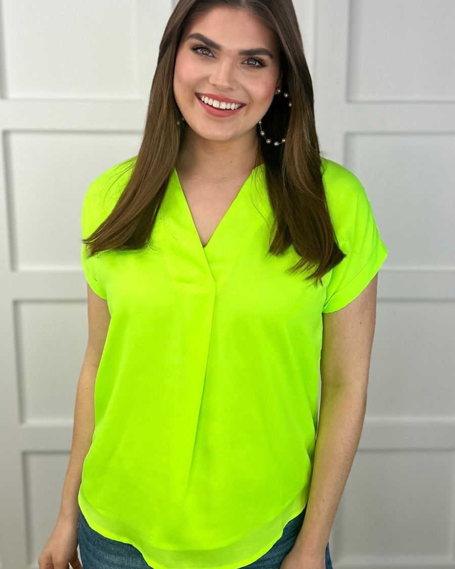 a vibrant neon lime blouse made of lightweight woven fabric blouse with a flattering draped silhouette, a contemporary V-neckline, rolled short sleeves, a fully lined interior, and no stretch