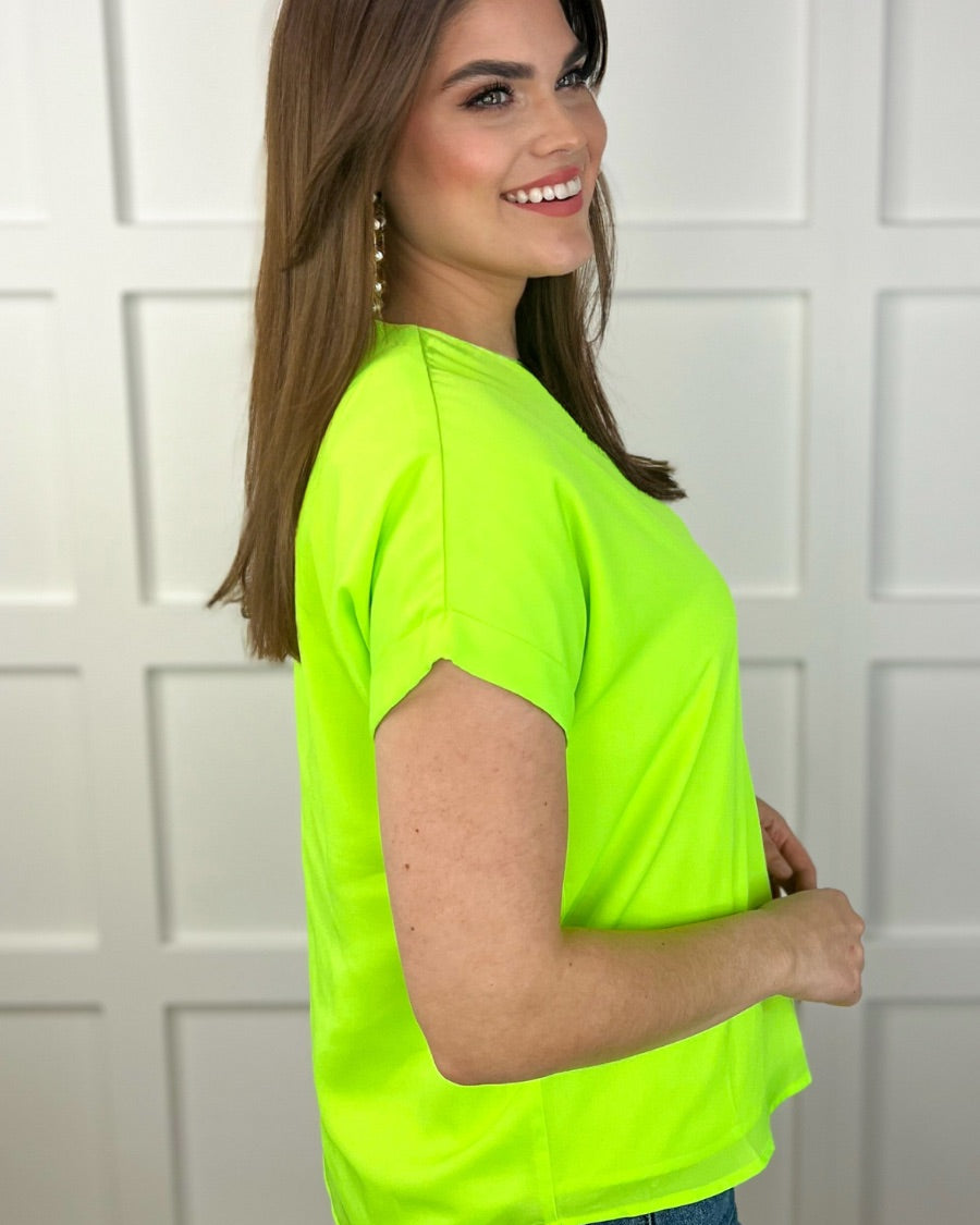 a vibrant neon lime blouse made of lightweight woven fabric blouse with a flattering draped silhouette, a contemporary V-neckline, rolled short sleeves, a fully lined interior, and no stretch