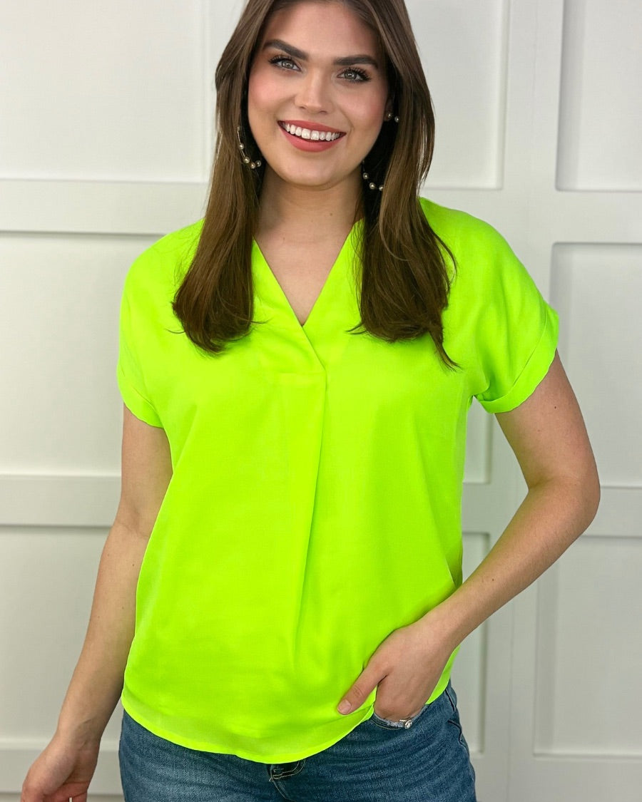 a vibrant neon lime blouse made of lightweight woven fabric blouse with a flattering draped silhouette, a contemporary V-neckline, rolled short sleeves, a fully lined interior, and no stretch