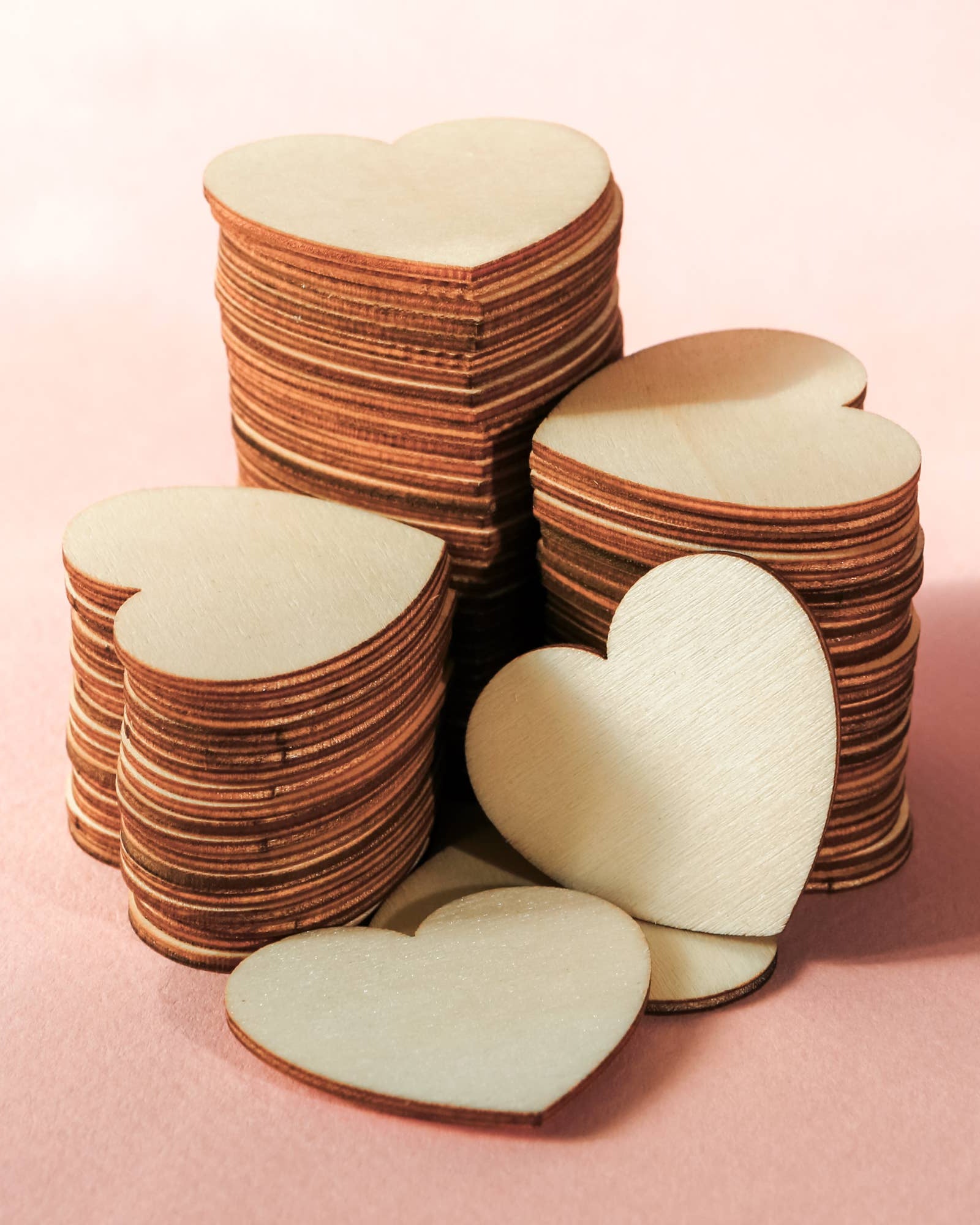 Stack of heart-shaped wooden cutouts on a pink background