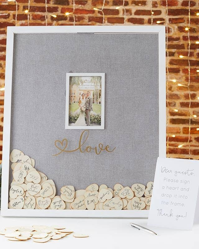 Decorative frame with 'love' text and heart-shaped wooden tokens against a brick wall background.