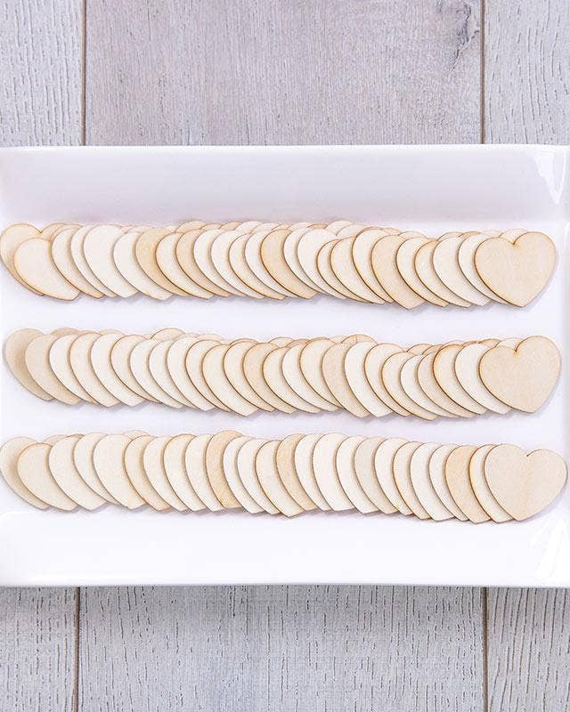 Wooden heart-shaped cutouts on a white paper bag with a wooden surface background
