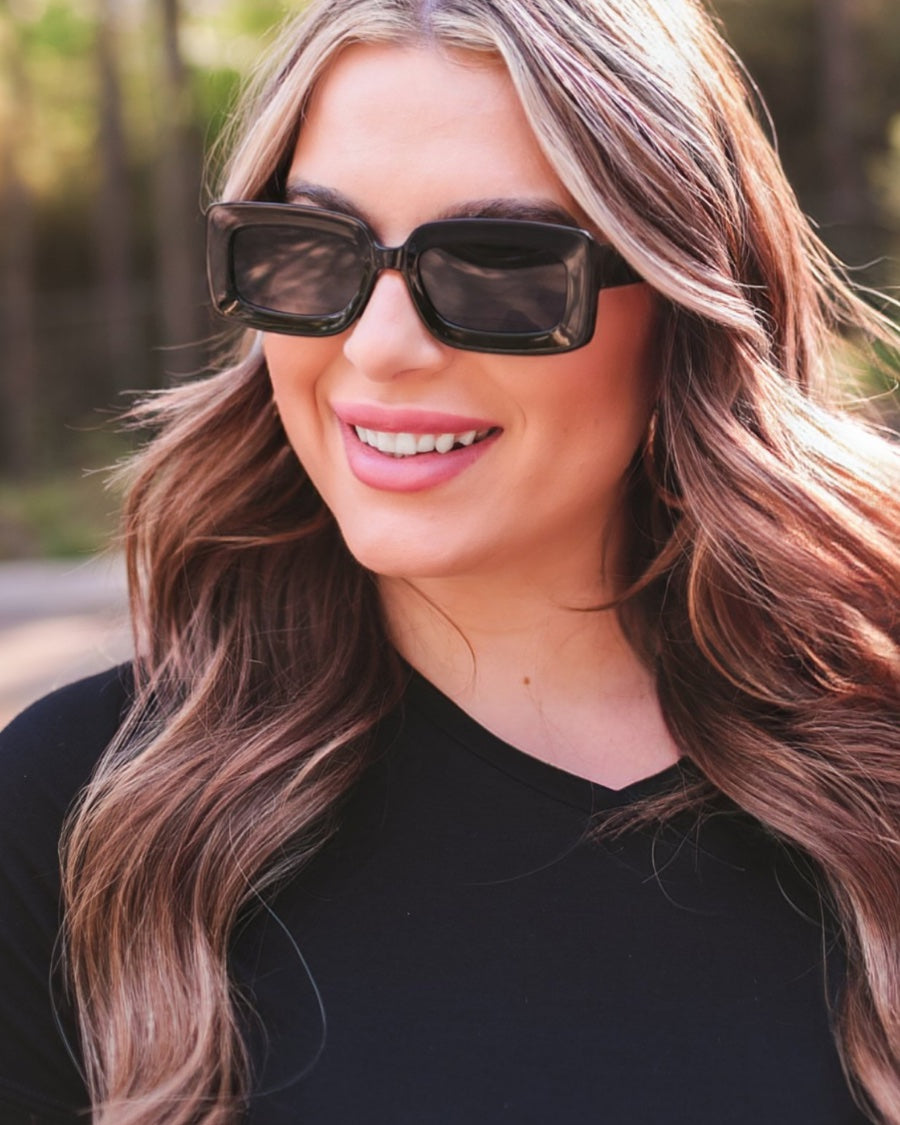 black chunky rectangular sunglasses with thick frames, tinted lenses, smooth finish, UV protection, and brand detail (on both the temple and the complimentary black pouch)
