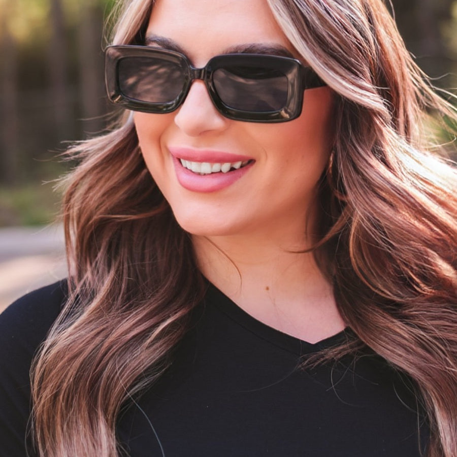 black chunky rectangular sunglasses with thick frames, tinted lenses, smooth finish, UV protection, and brand detail (on both the temple and the complimentary black pouch)