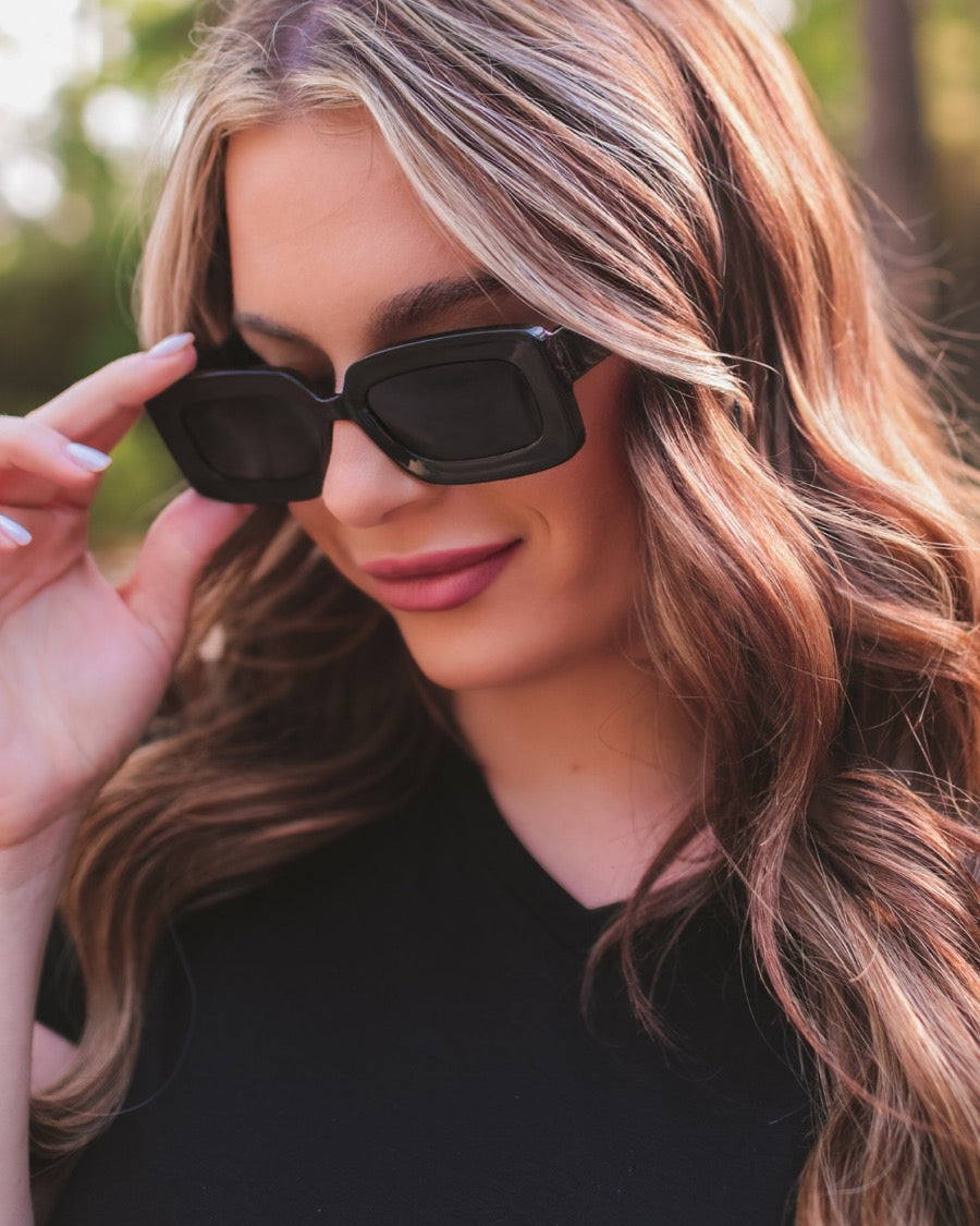 black chunky rectangular sunglasses with thick frames, tinted lenses, smooth finish, UV protection, and brand detail (on both the temple and the complimentary black pouch)