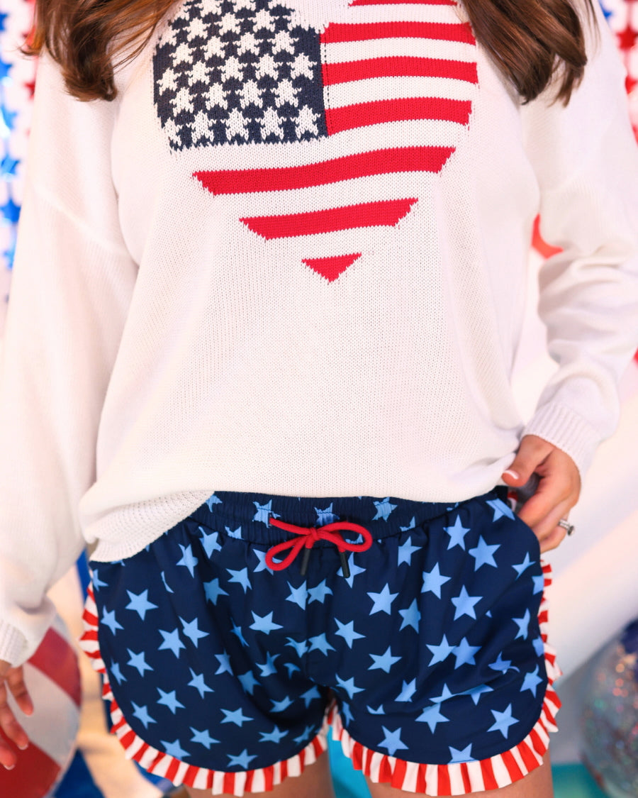 mid-rise relaxed fit activewear shorts with side pockets and a red tie waist drawstring finished with black aglets, designed on a two-tone blue star pattern print and red-and-white ruffle trim