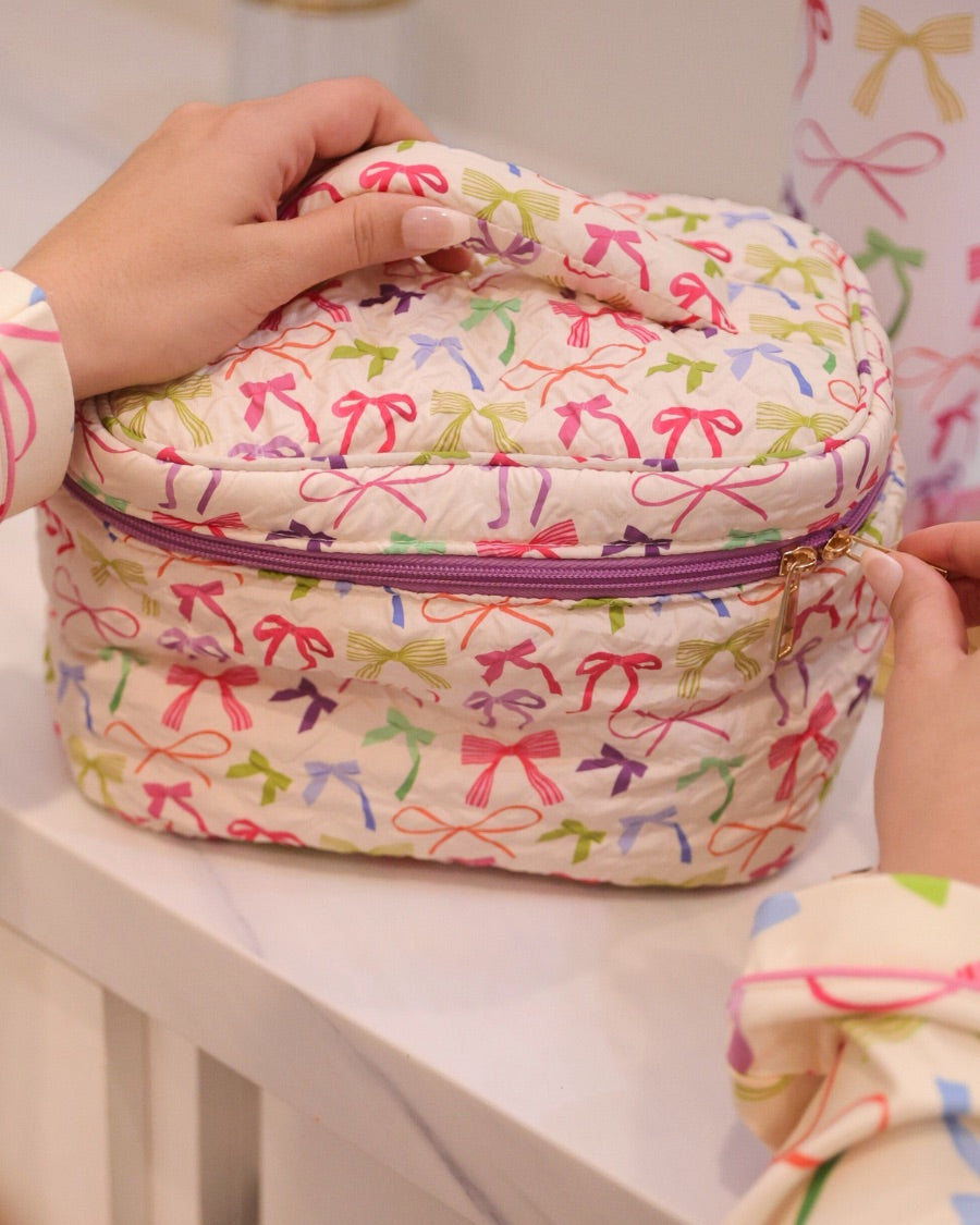 a structured bag with a spacious interior, a secure double zip around closure, a top handle, and gold accents on a quilted body in daylight bow (multi)