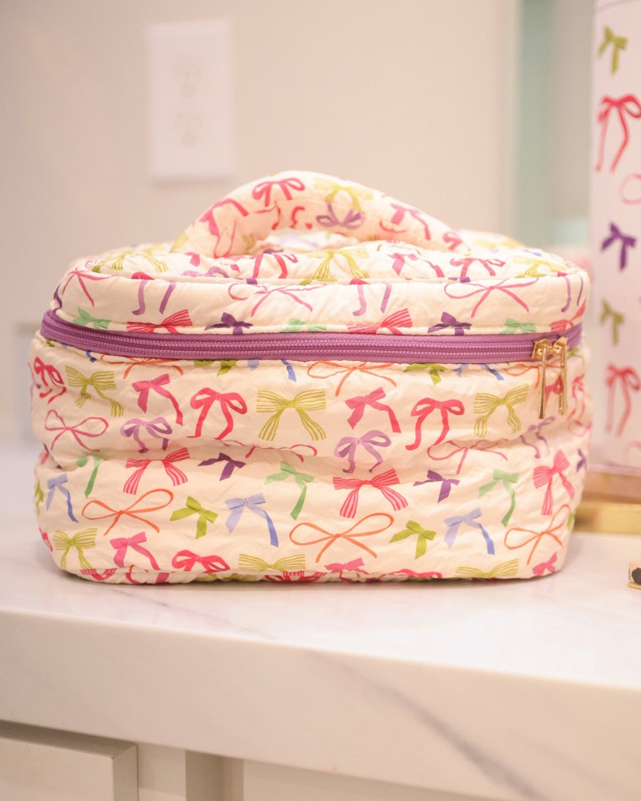 a structured bag with a spacious interior, a secure double zip around closure, a top handle, and gold accents on a quilted body in daylight bow (multi)