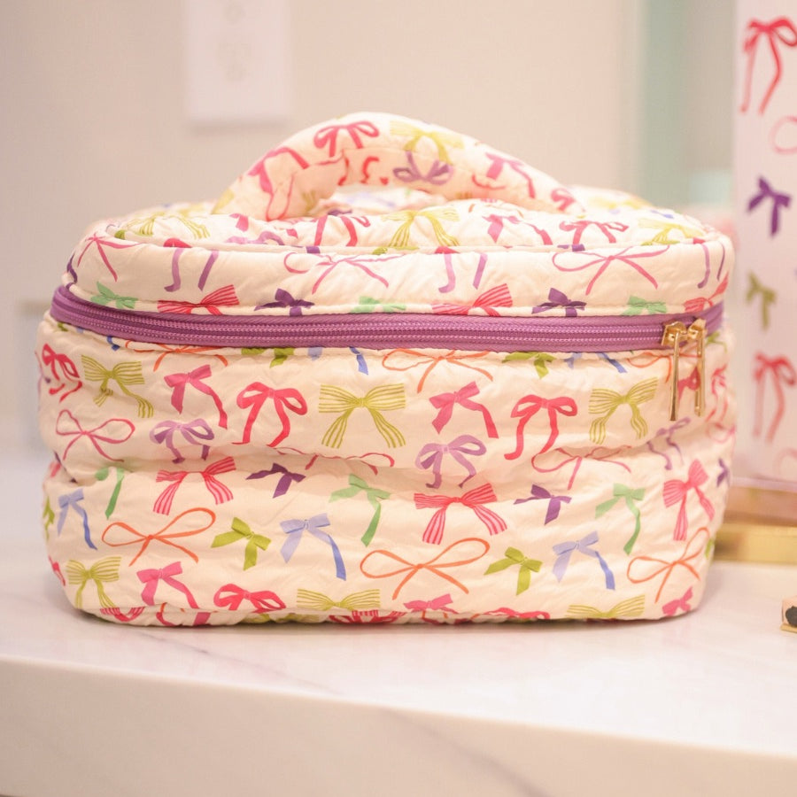 a structured bag with a spacious interior, a secure double zip around closure, a top handle, and gold accents on a quilted body in daylight bow (multi)