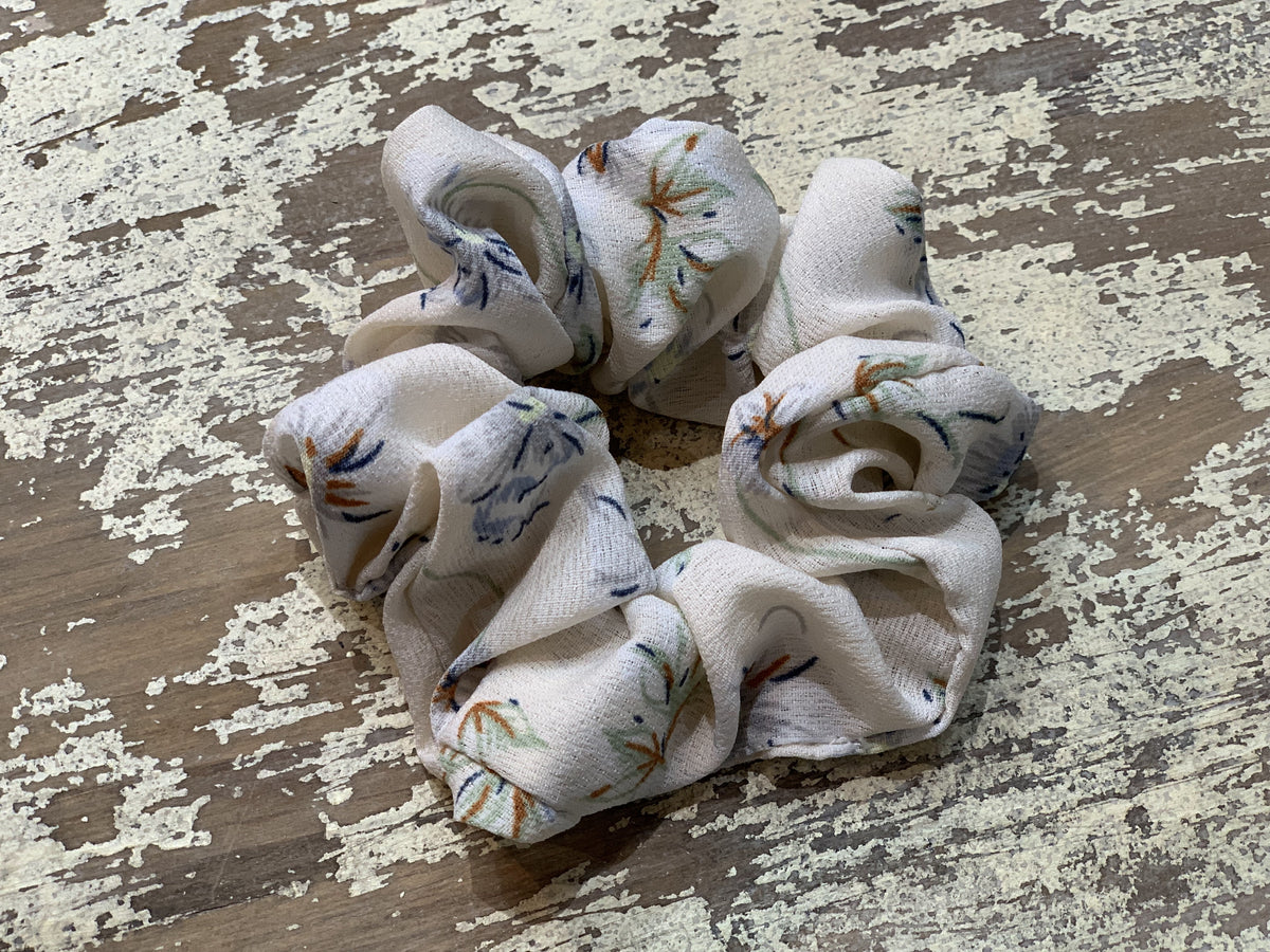 an oversized floral scrunchie with lightweight textured fabric, gathered construction, gentle hair-friendly hold, and easy pull-on styling in cream
