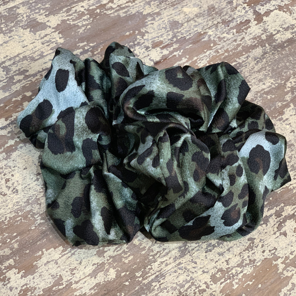 an oversized satin-look leopard scrunchie with glossy animal print fabric, plush gathered construction, lightweight feel, and gentle hair-friendly hold in leopard teal