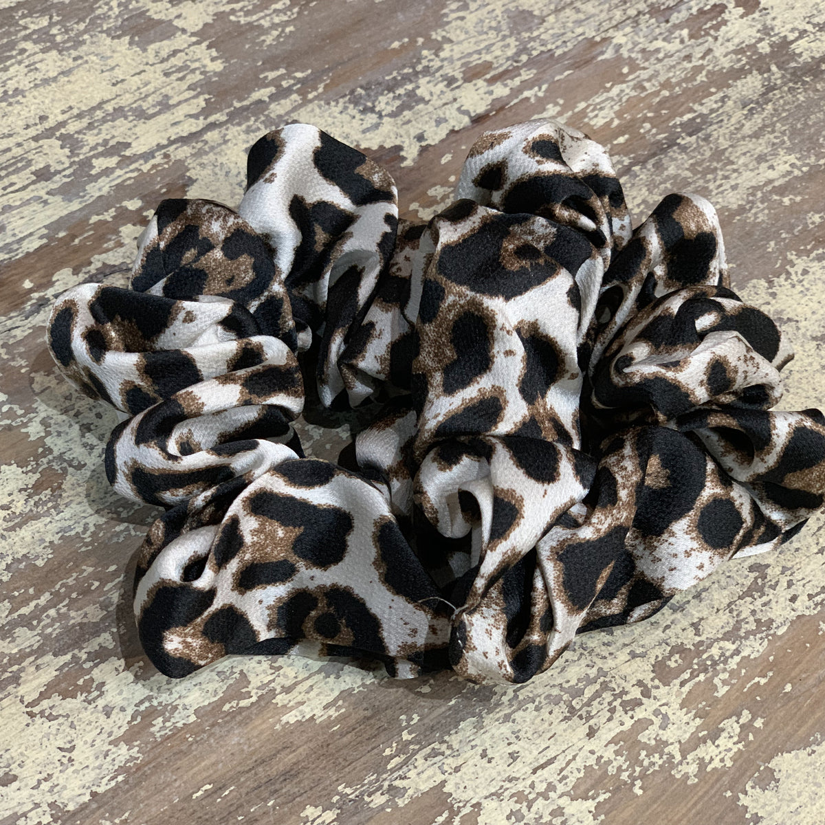 an oversized satin-look leopard scrunchie with glossy animal print fabric, plush gathered construction, lightweight feel, and gentle hair-friendly hold in leopard white