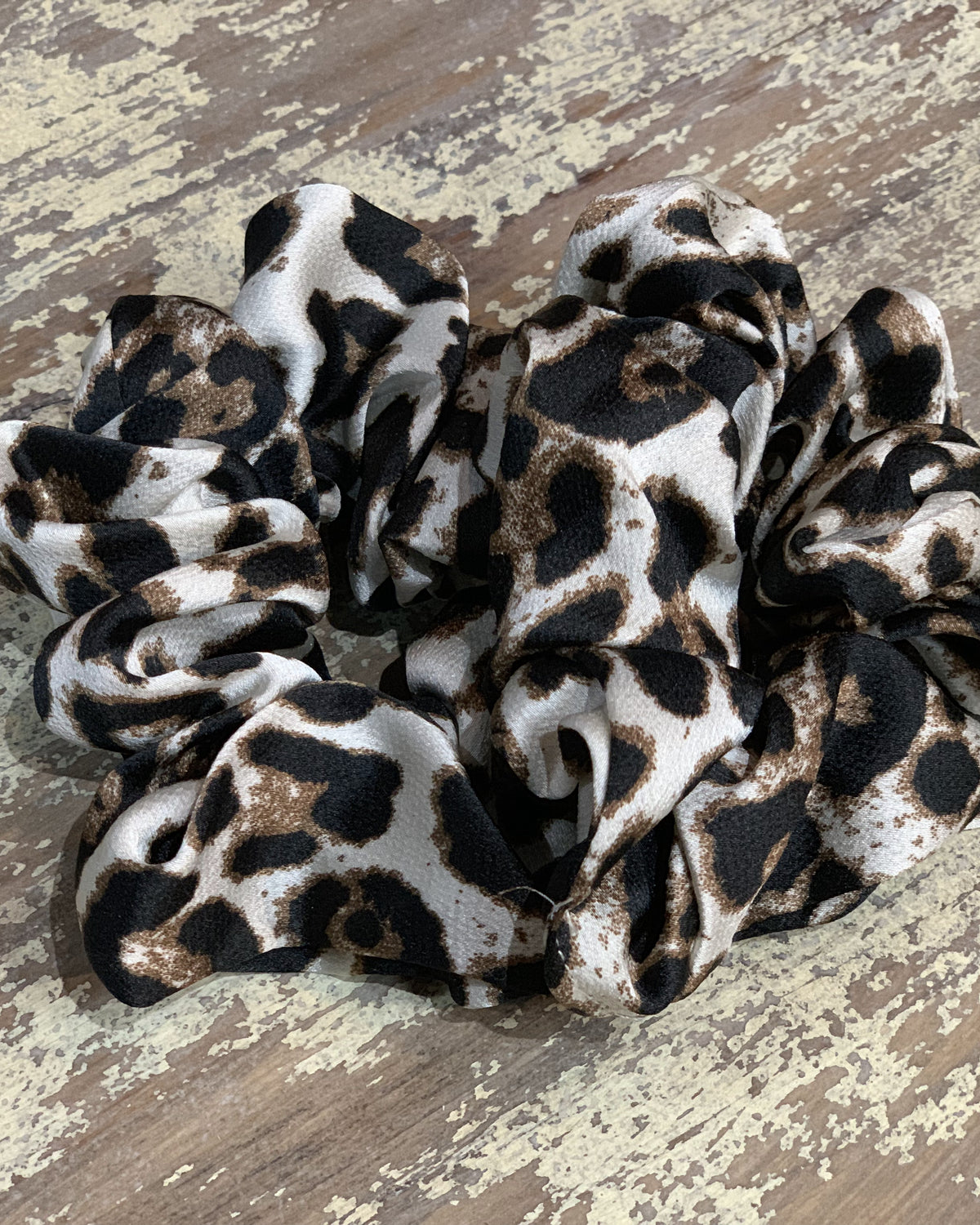 an oversized satin-look leopard scrunchie with glossy animal print fabric, plush gathered construction, lightweight feel, and gentle hair-friendly hold in leopard white