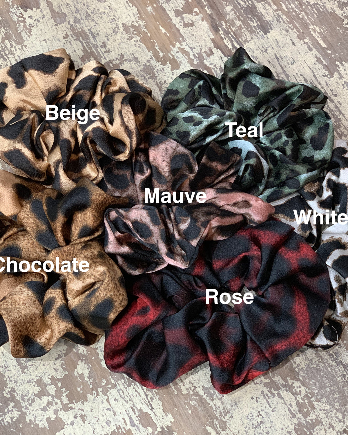 oversized satin-look leopard scrunchies with glossy animal print fabric, plush gathered construction, lightweight feel, and gentle hair-friendly hold in beige, chocolate, mauve, rose, teal, and white