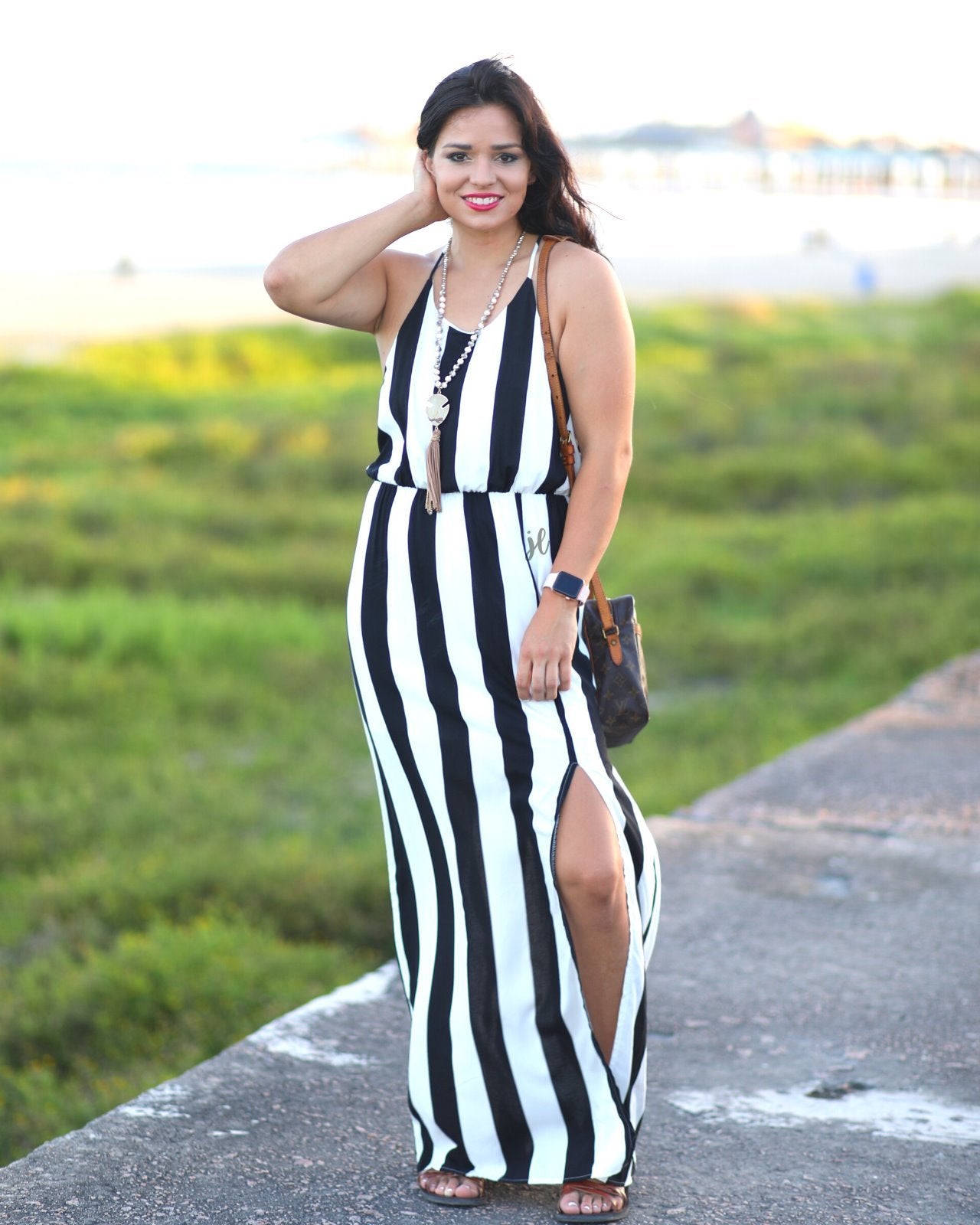 sleeveless maxi dress made of lightweight material with non-adjustable crisscross spaghetti straps, a left side slit, and interior lining, designed on a black and white vertical striped pattern fabric