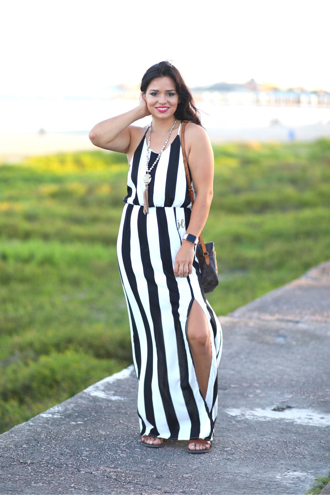 sleeveless maxi dress made of lightweight material with non-adjustable crisscross spaghetti straps, a left side slit, and interior lining, designed on a black and white vertical striped pattern fabric