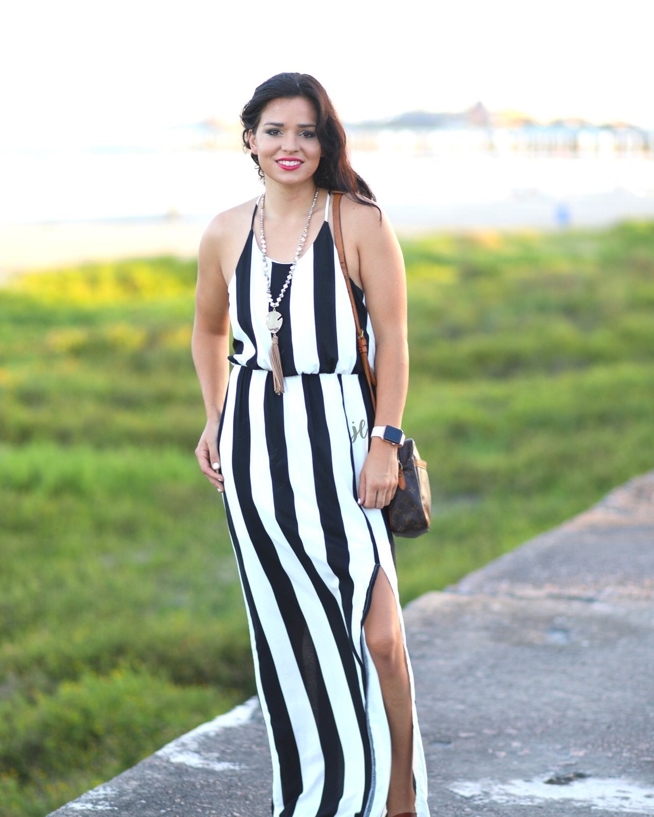 sleeveless maxi dress made of lightweight material with non-adjustable crisscross spaghetti straps, a left side slit, and interior lining, designed on a black and white vertical striped pattern fabric