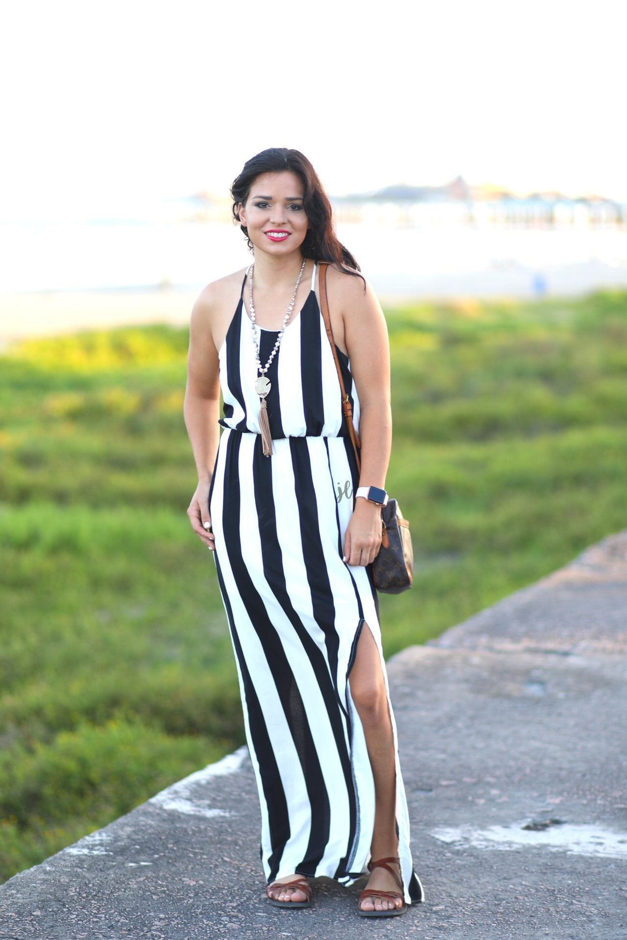 sleeveless maxi dress made of lightweight material with non-adjustable crisscross spaghetti straps, a left side slit, and interior lining, designed on a black and white vertical striped pattern fabric