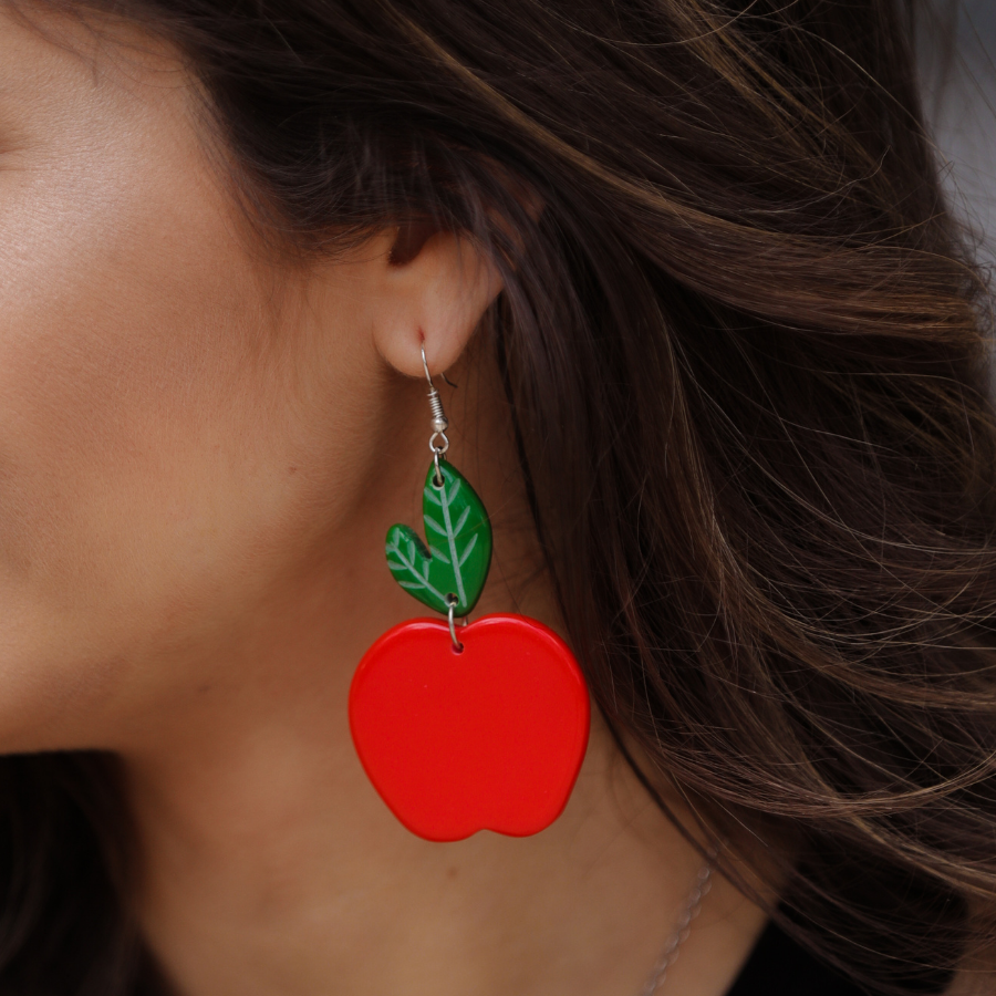 dangle earrings with a bold red apple in a glossy finish, a bright green leaf detail, and silver fish hooks