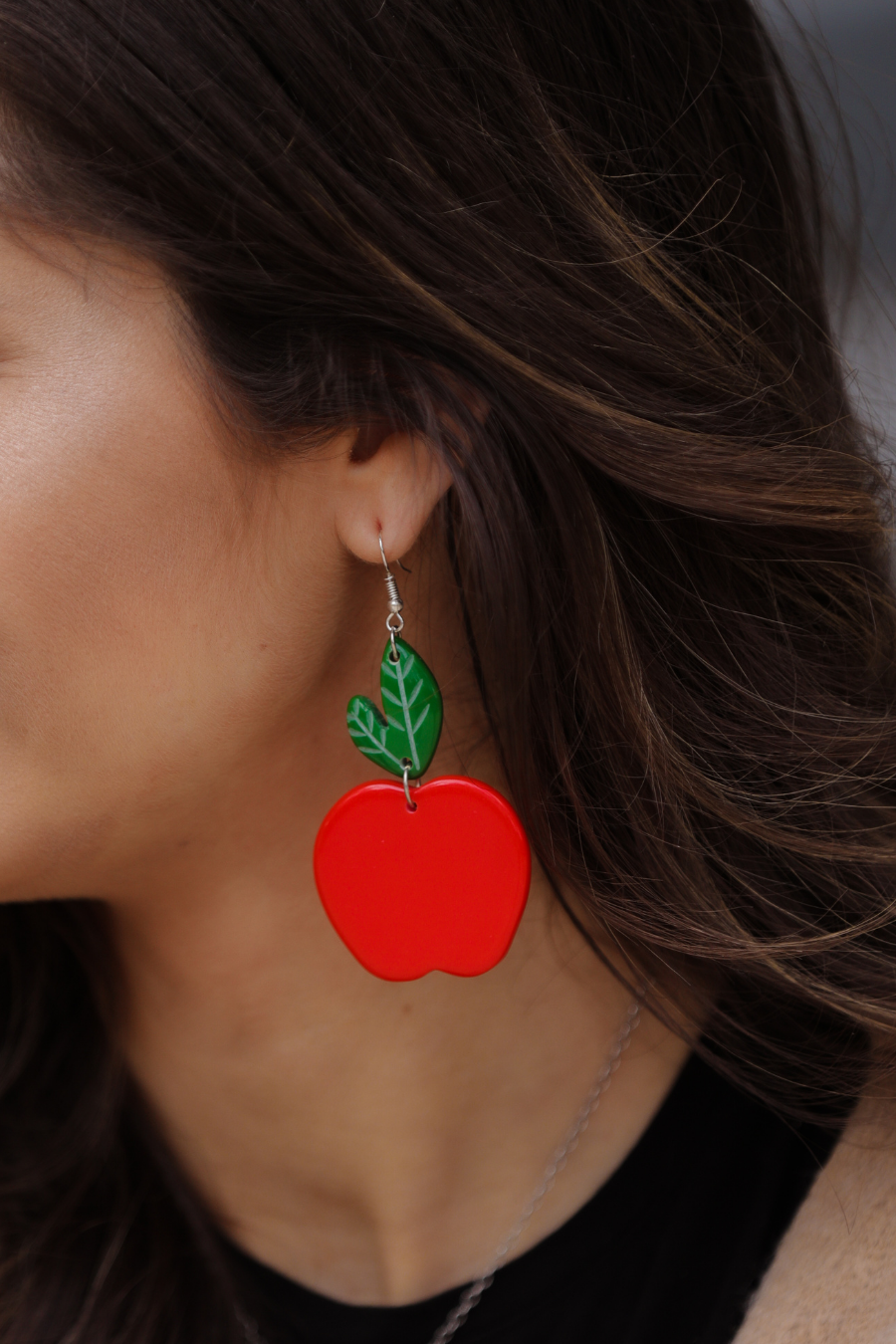 dangle earrings with a bold red apple in a glossy finish, a bright green leaf detail, and silver fish hooks