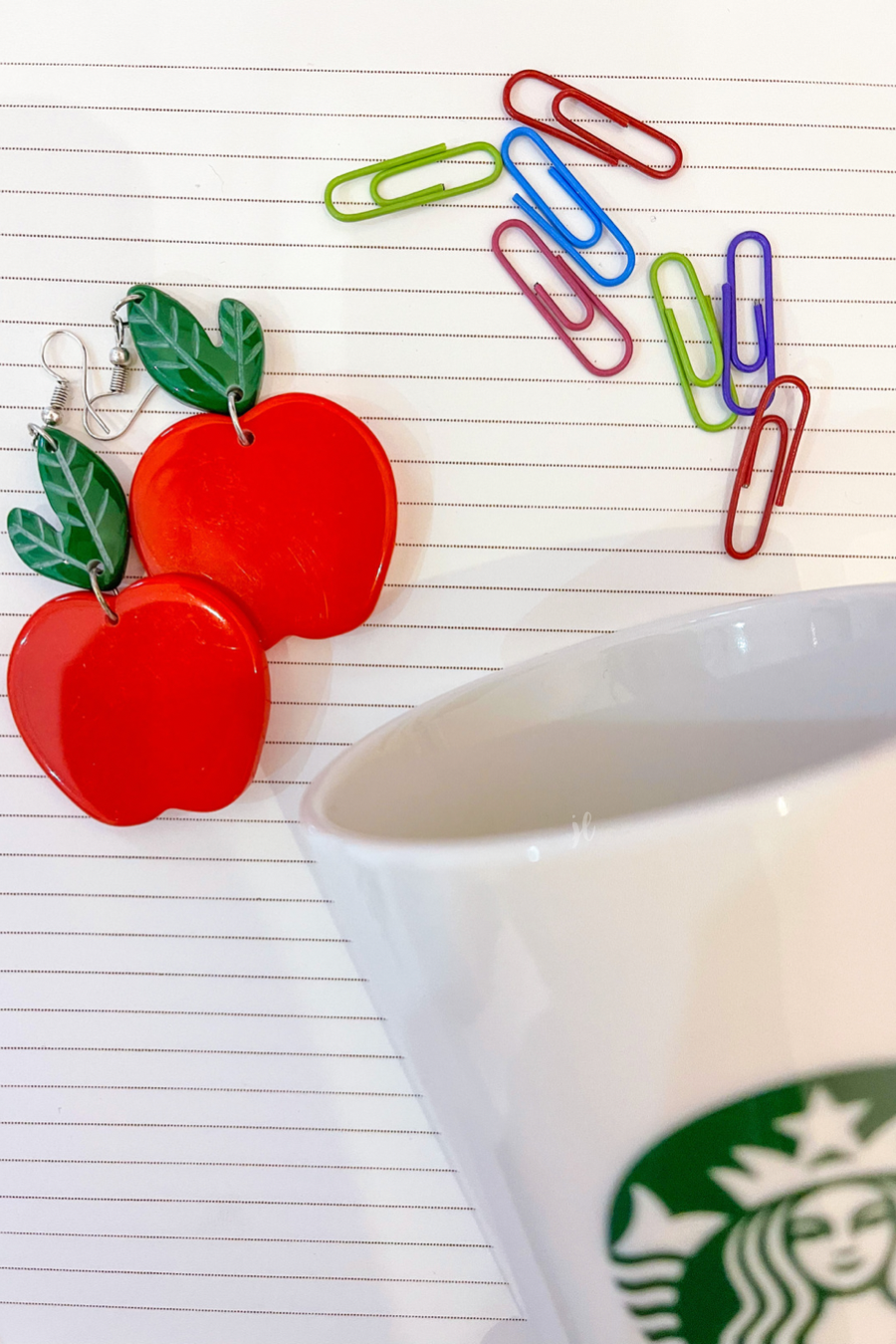 dangle earrings with a bold red apple in a glossy finish, a bright green leaf detail, and silver fish hooks