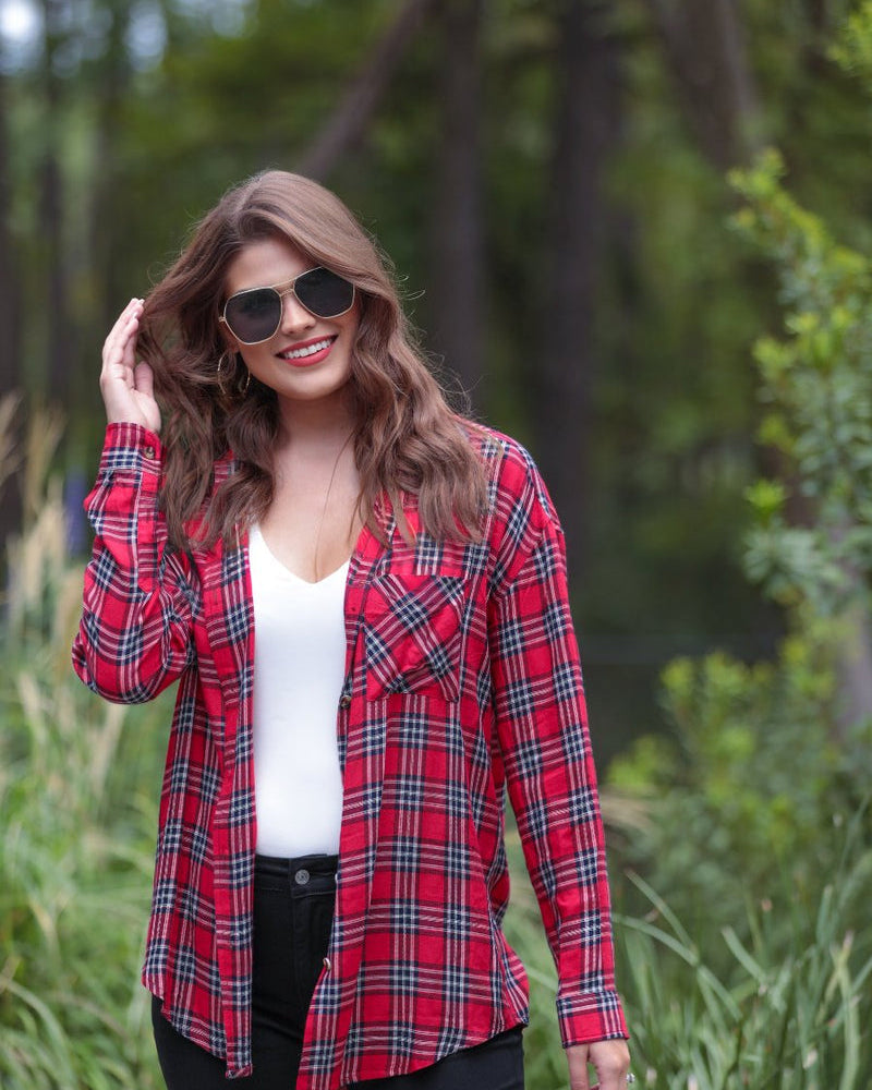 lightweight top with functional buttons, a collared neckline, roll-tab long sleeves, and a high low round hemline on a red plaid pattern