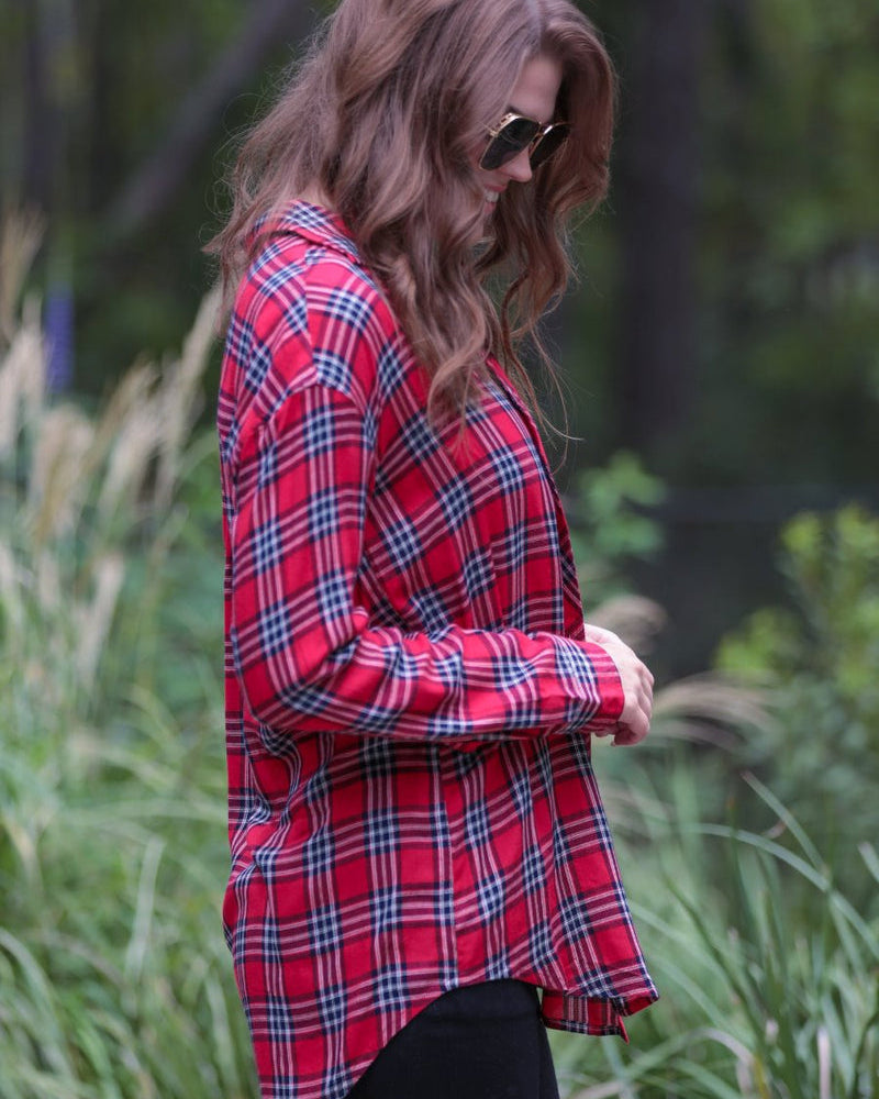 lightweight top with functional buttons, a collared neckline, roll-tab long sleeves, and a high low round hemline on a red plaid pattern