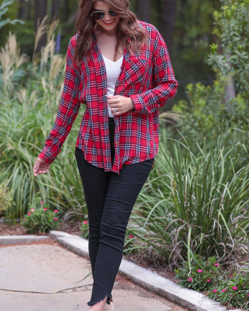 lightweight top with functional buttons, a collared neckline, roll-tab long sleeves, and a high low round hemline on a red plaid pattern