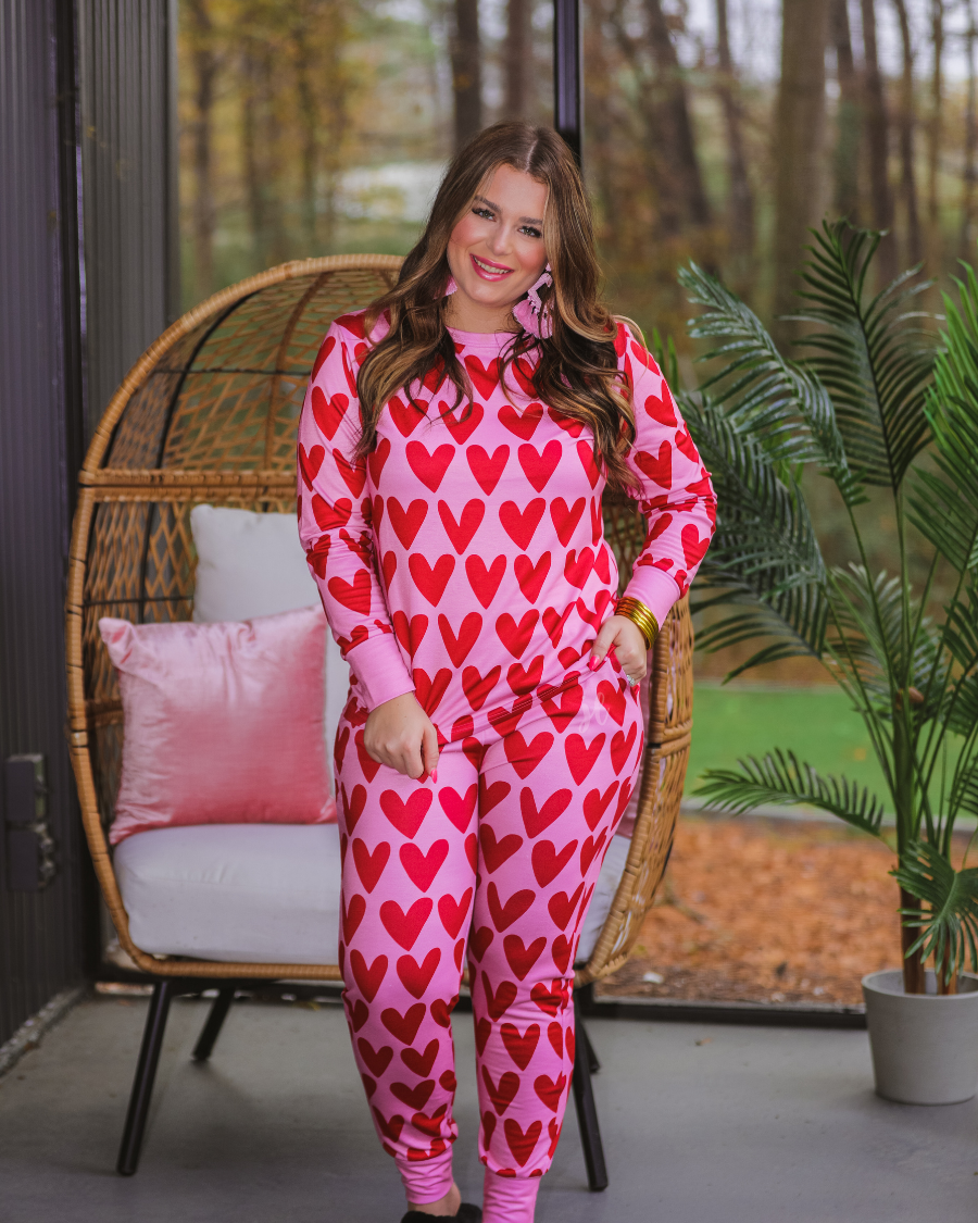 long-sleeve top with red hearts on a solid pink fabric and a rounded neckline paired with matching elastic waistband bottoms